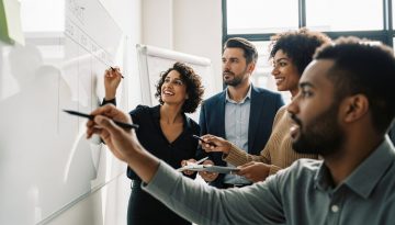Ein engagiertes Projektteam diskutiert während eines Kick-Off Meetings an einem Whiteboard.