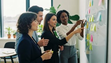 Ein Team von Fachleuten bei einem Workshop zur Führungskräfteentwicklung, die an einem Whiteboard Strategien erarbeiten.